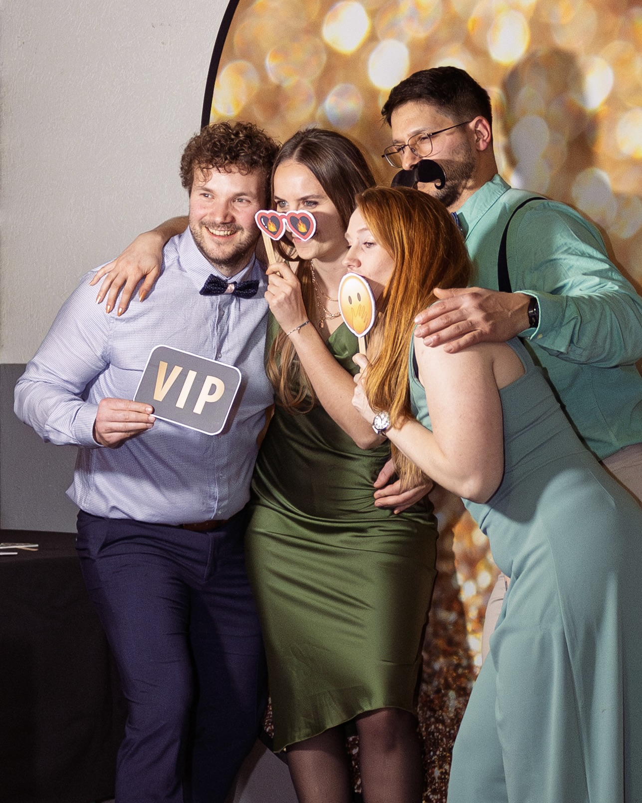 Groupe de personnes souriantes tenant des accessoires festifs devant un photobooth lors d’un événement.