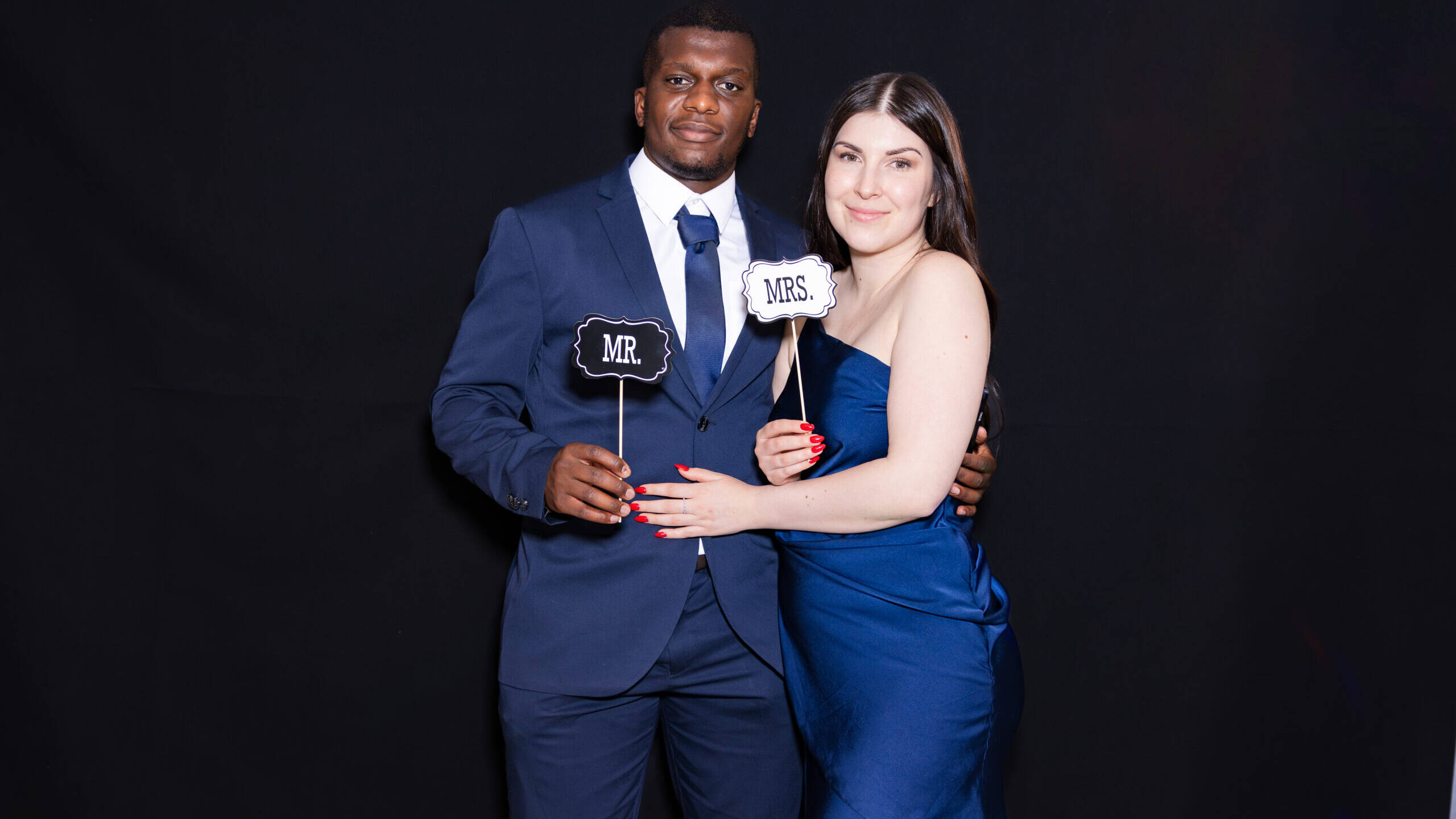 Jeune couple posant avec complicité devant un photobooth EnjoyBooth décoré pour un mariage à Fribourg